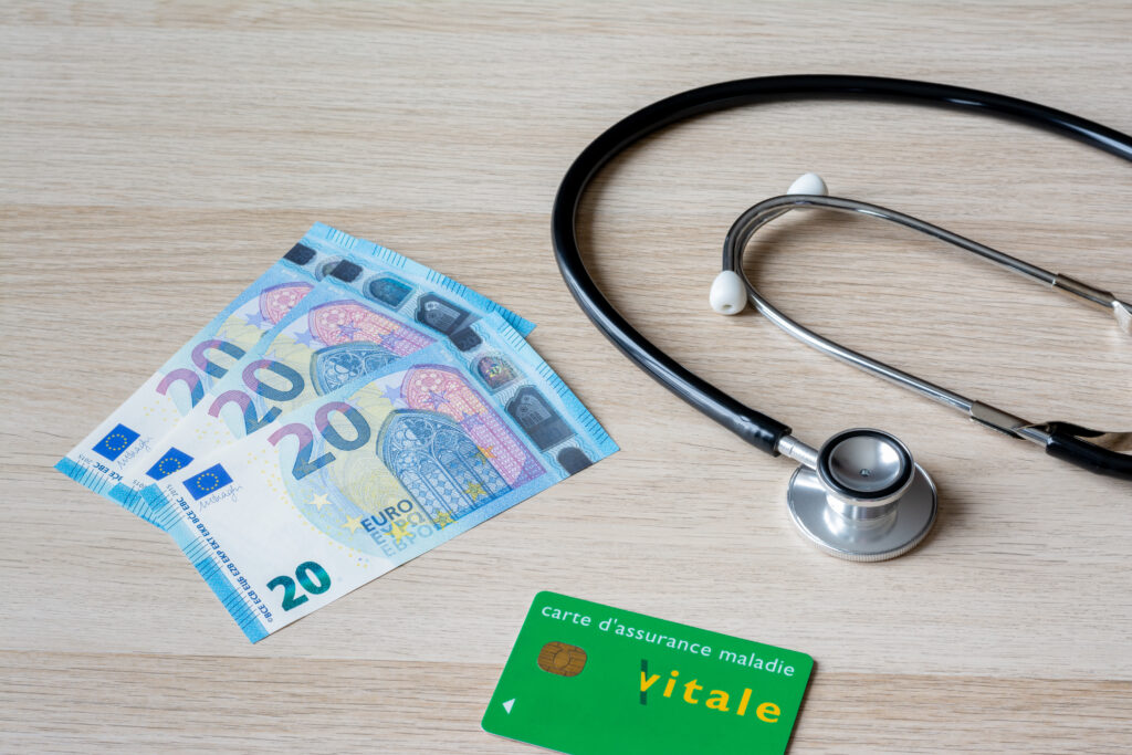 Dépassements d'honoraires illustrés par 60 euros en liquide, carte Vitale et stéthoscope