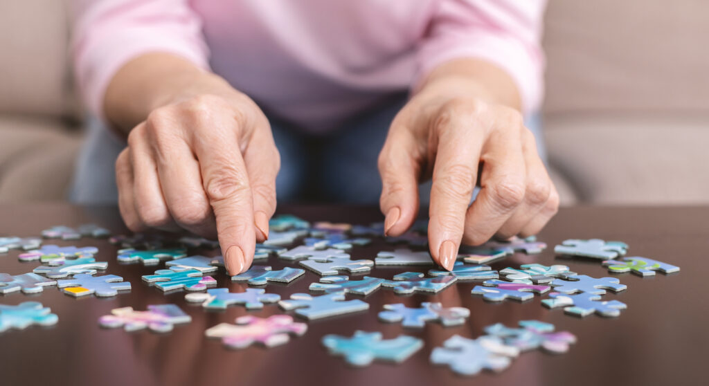Mains de femme qui assemblent un puzzle, symbole d’espoir et d’accompagnement face à la maladie d’Alzheimer